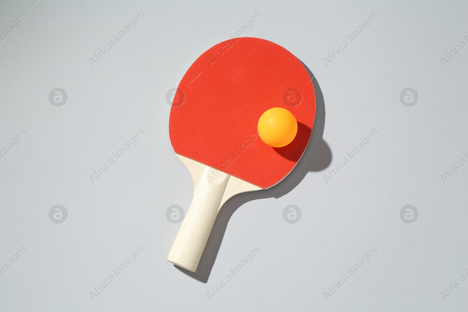 Ping pong racket and ball on light background, top view Photo of Ping pong racket and ball on light background, top view