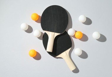 Photo of Ping pong rackets and balls on light background, flat lay