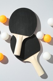 Photo of Ping pong rackets and balls on light background, flat lay