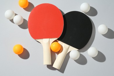 Photo of Ping pong rackets and balls on light background, flat lay