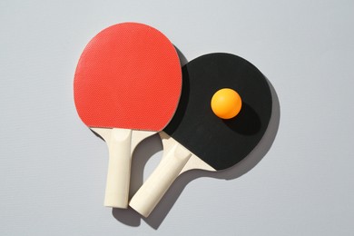 Photo of Ping pong rackets and ball on light background, top view