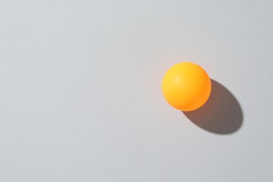 Photo of One ping pong ball on light background, top view. Space for text
