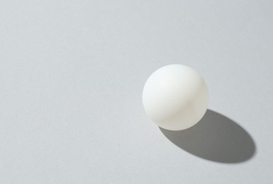 Photo of One ping pong ball on light background. Space for text