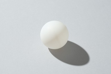Photo of One ping pong ball on light background, closeup