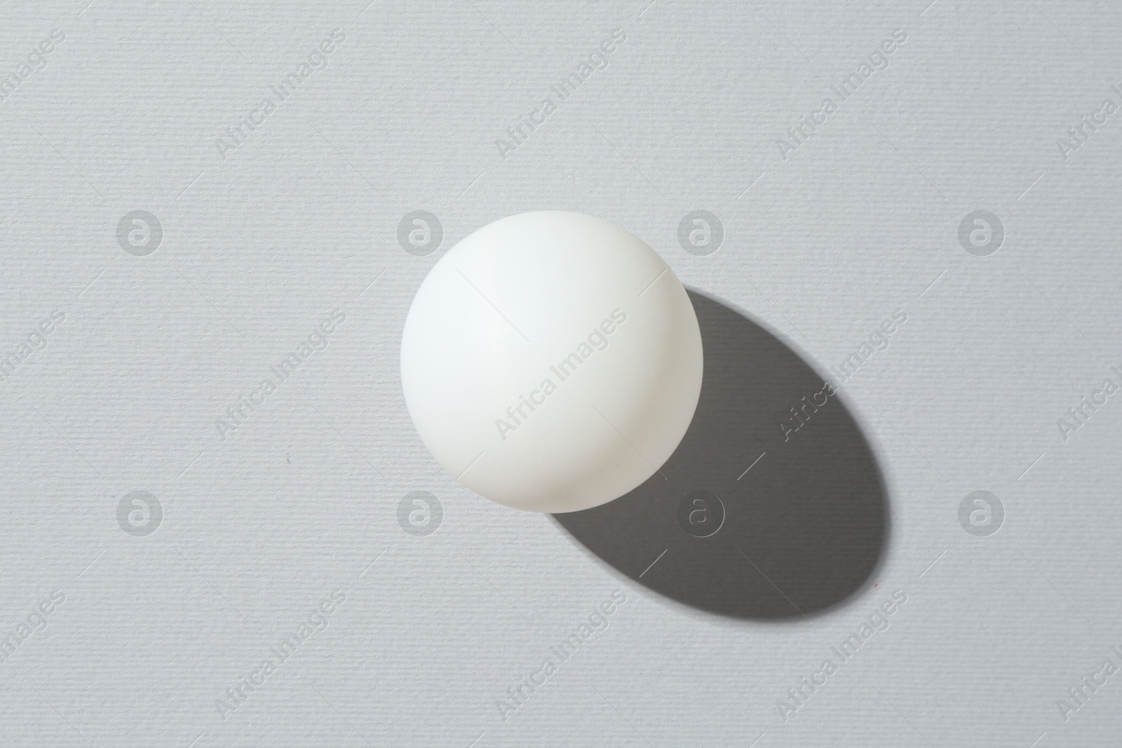 One ping pong ball on light background, top view Photo of One ping pong ball on light background, top view