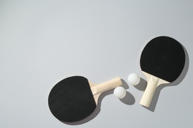 Photo of Ping pong rackets and balls on light background, flat lay. Space for text