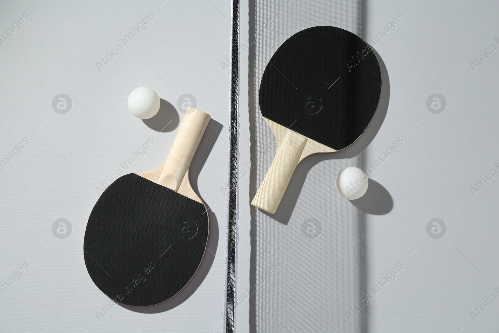 Ping pong rackets, balls and net on light background, flat lay Photo of Ping pong rackets, balls and net on light background, flat lay