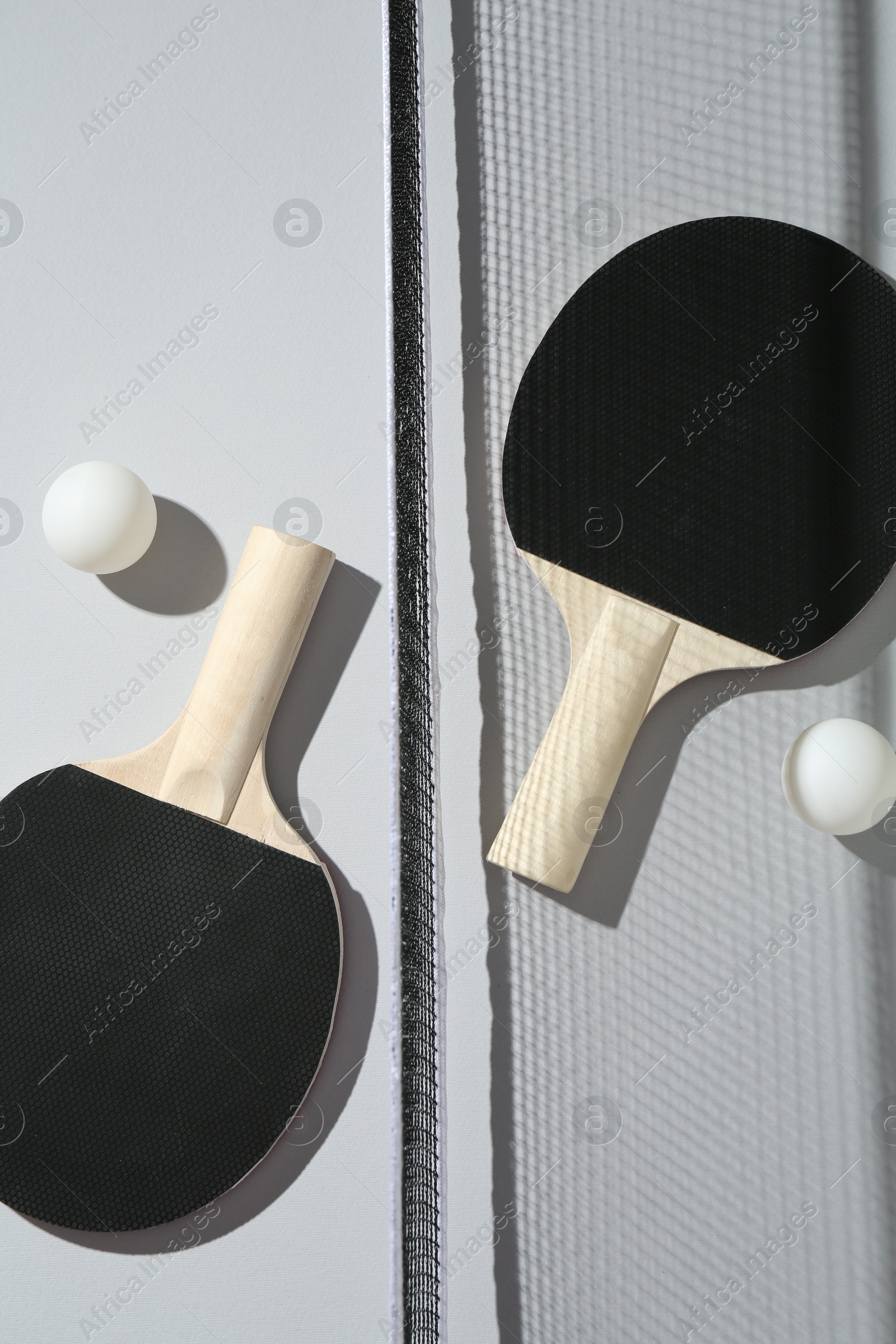 Ping pong rackets, balls and net on light background, flat lay Photo of Ping pong rackets, balls and net on light background, flat lay