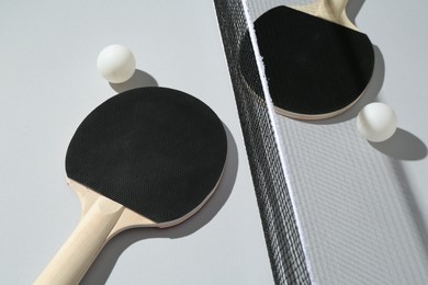 Photo of Ping pong rackets, balls and net on light background