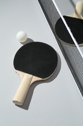 Photo of Ping pong rackets, ball and net on light background