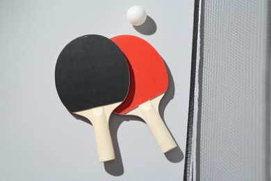 Photo of Ping pong rackets, ball and net on light background, flat lay