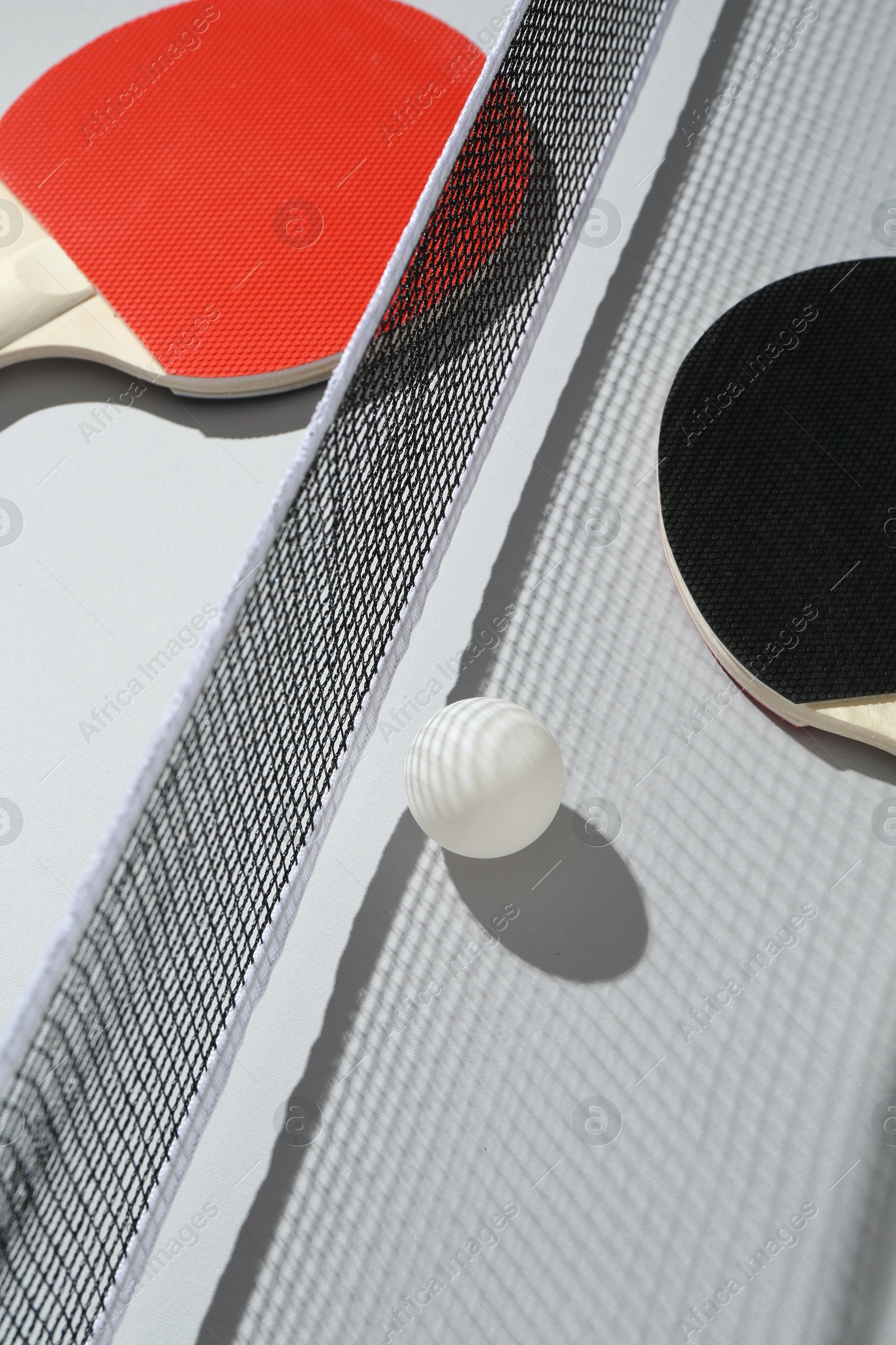 Ping pong rackets, ball and net on light background Photo of Ping pong rackets, ball and net on light background