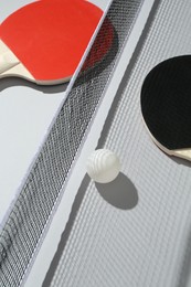 Photo of Ping pong rackets, ball and net on light background