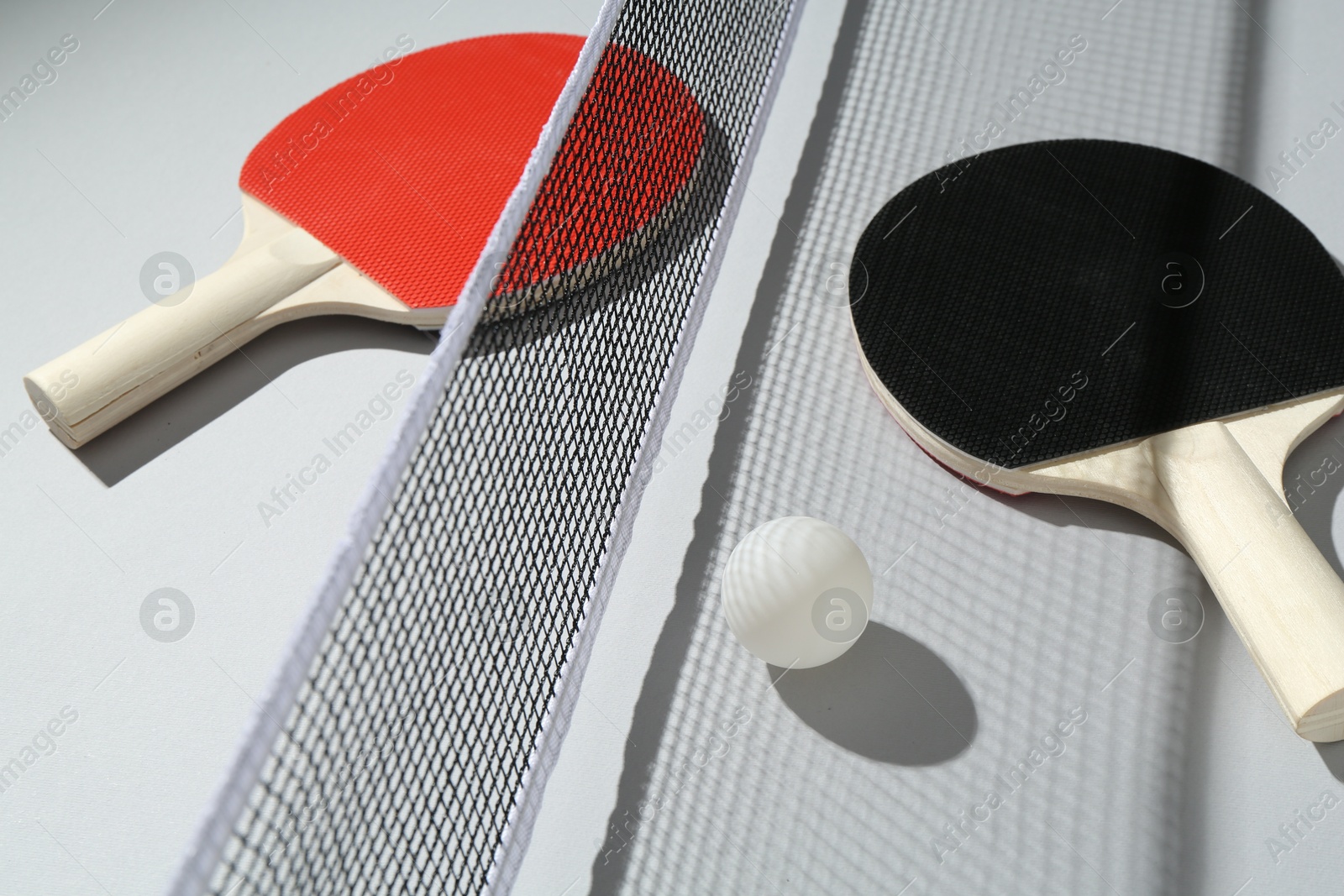Ping pong rackets, ball and net on light background Photo of Ping pong rackets, ball and net on light background