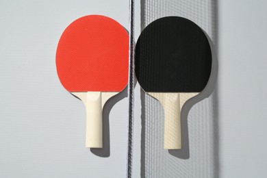 Photo of Ping pong rackets and net on light background, top view