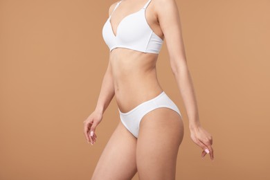 Photo of Woman with perfect slim body on beige background, closeup
