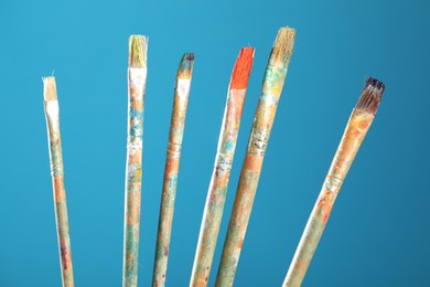 Photo of Dirty paintbrushes on light blue background, closeup