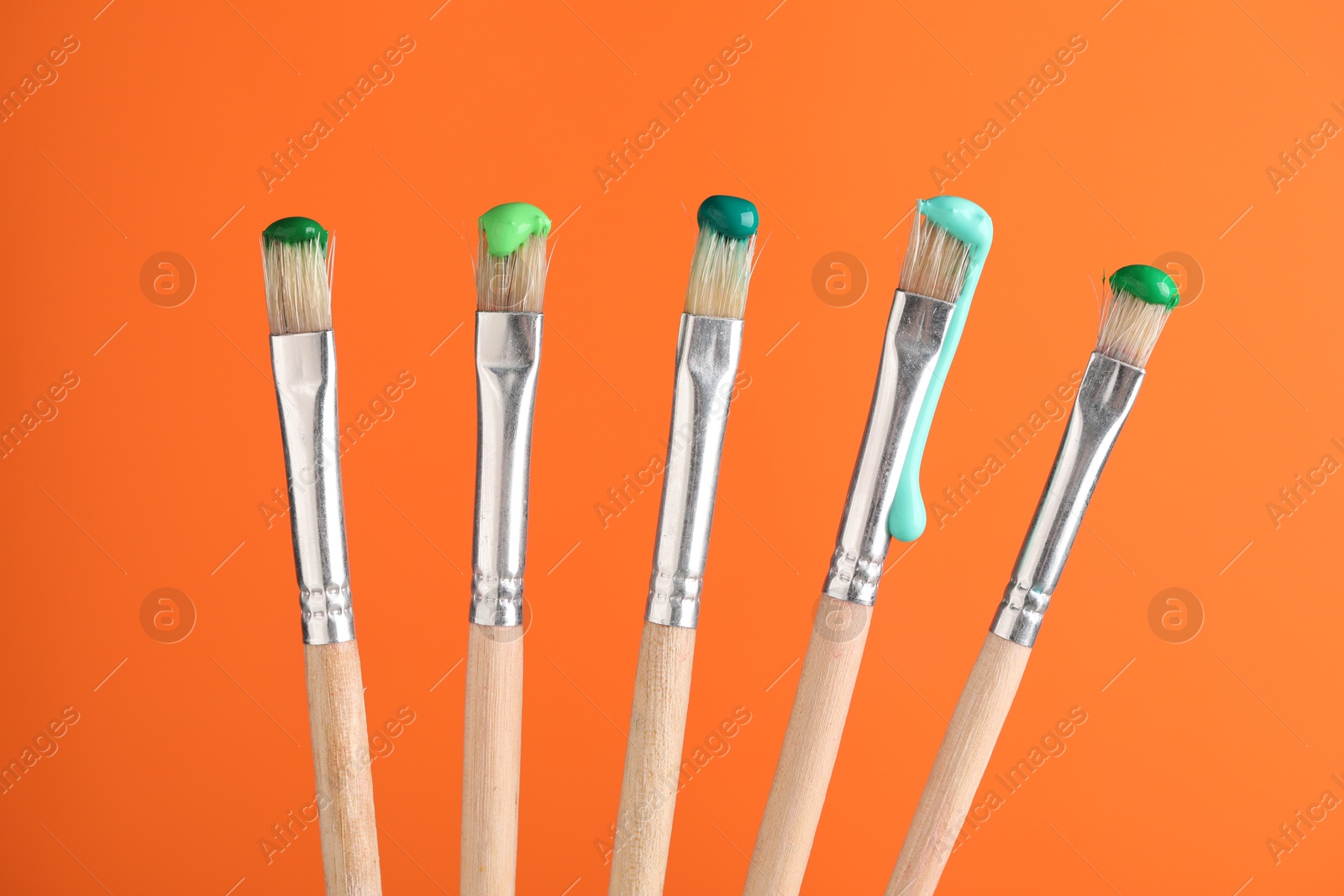 Many brushes with color paints on orange background, closeup Photo of Many brushes with color paints on orange background, closeup