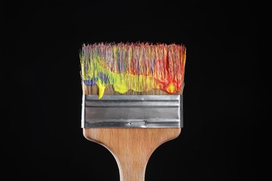 Photo of One dirty paintbrush on black background, closeup