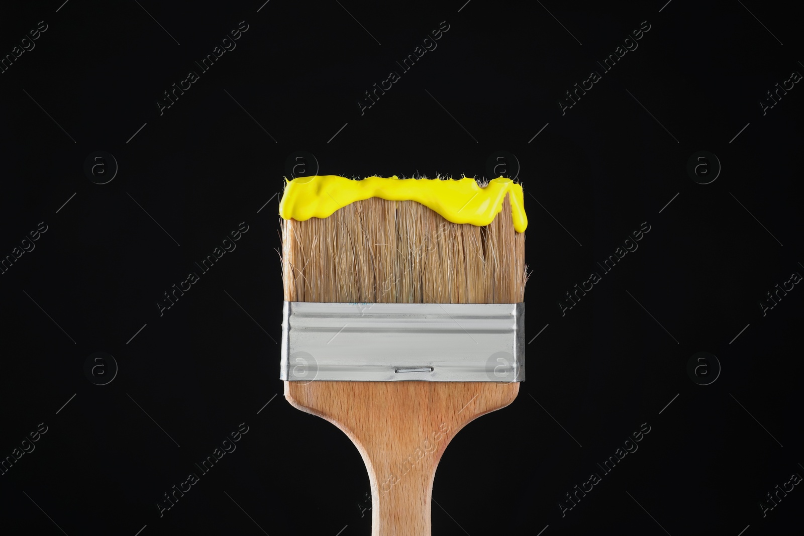 Brush with yellow paint on black background, closeup Photo of Brush with yellow paint on black background, closeup