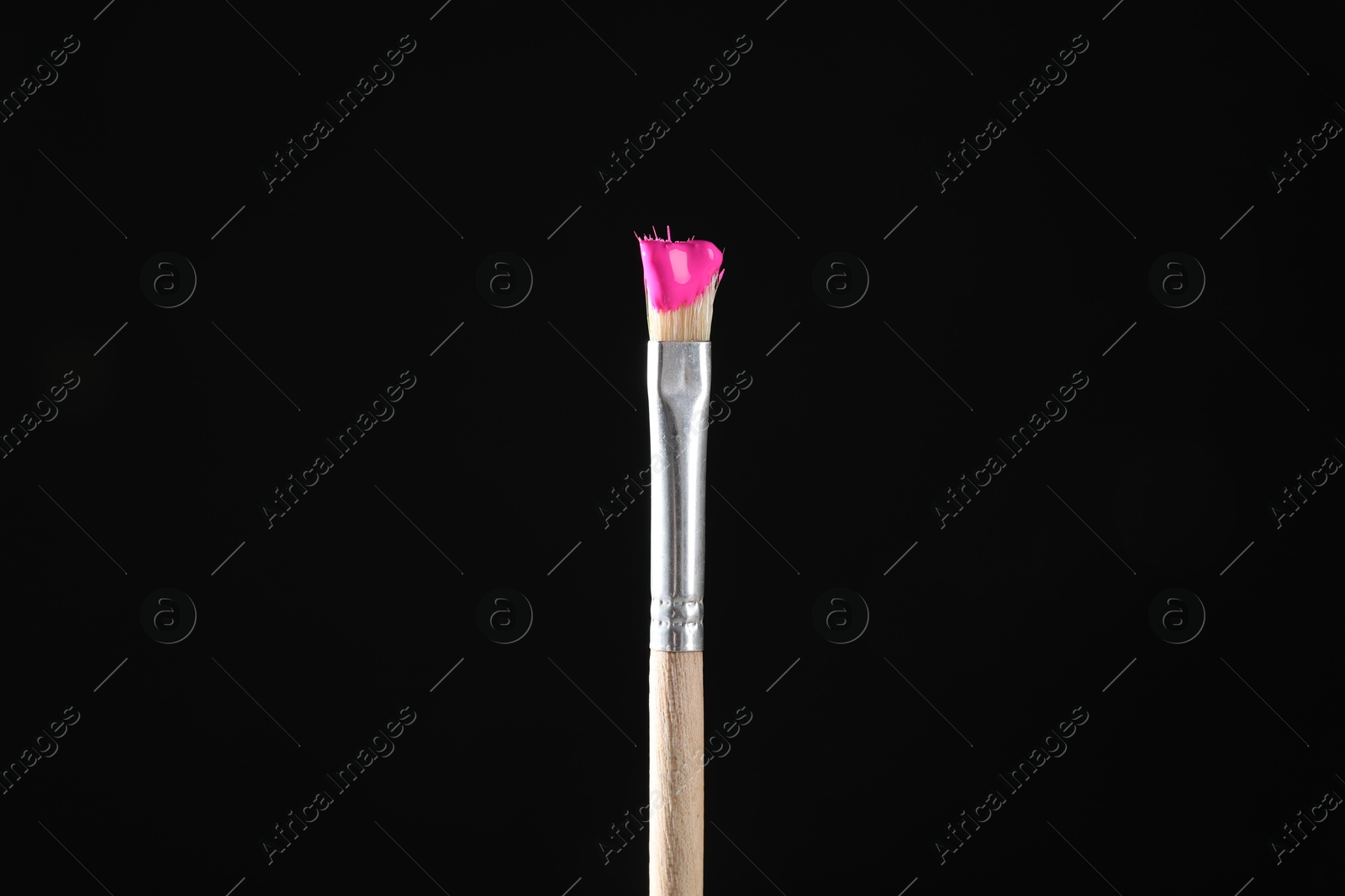 Brush with pink paint on black background, closeup Photo of Brush with pink paint on black background, closeup