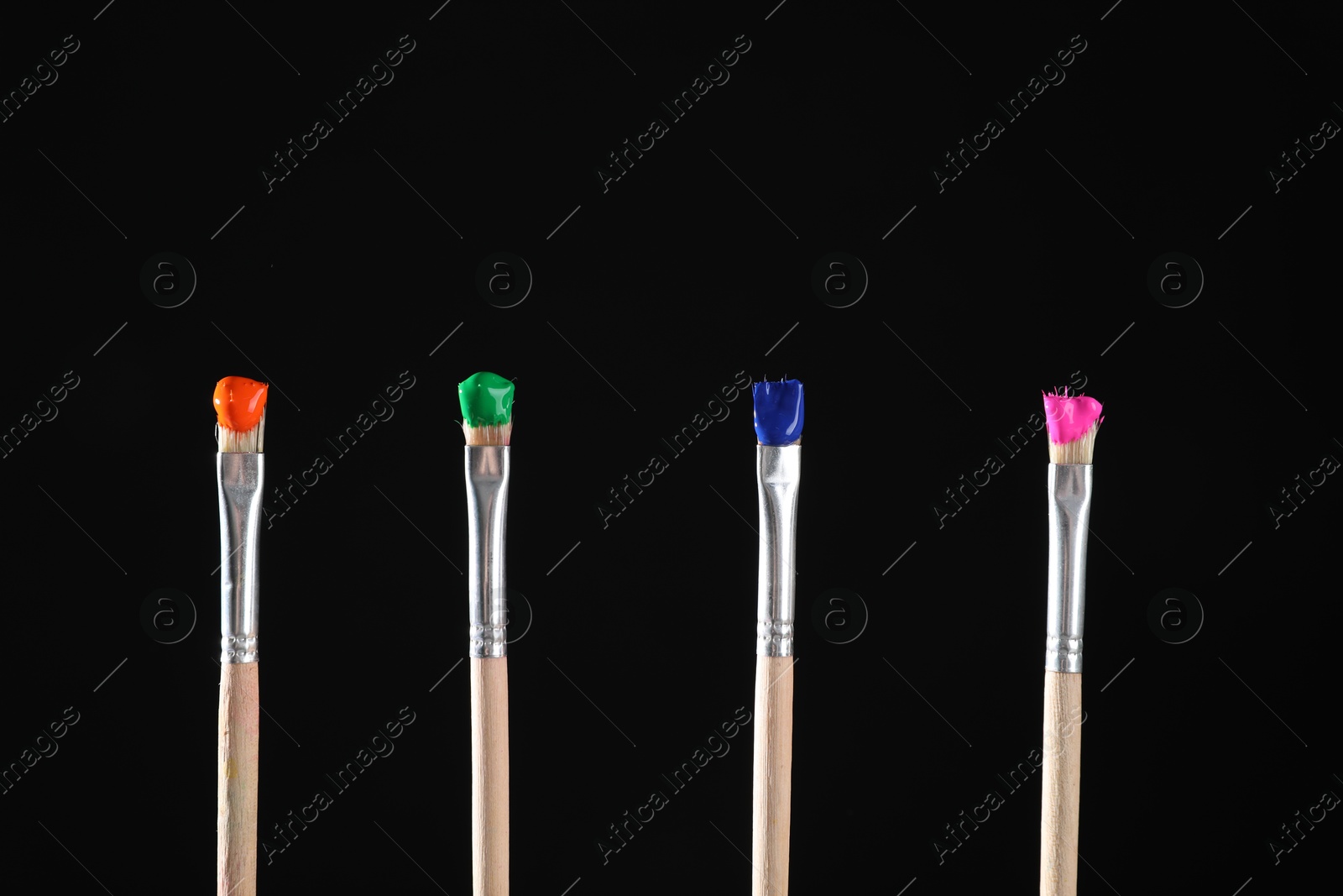 Many brushes with color paints on black background, closeup Photo of Many brushes with color paints on black background, closeup
