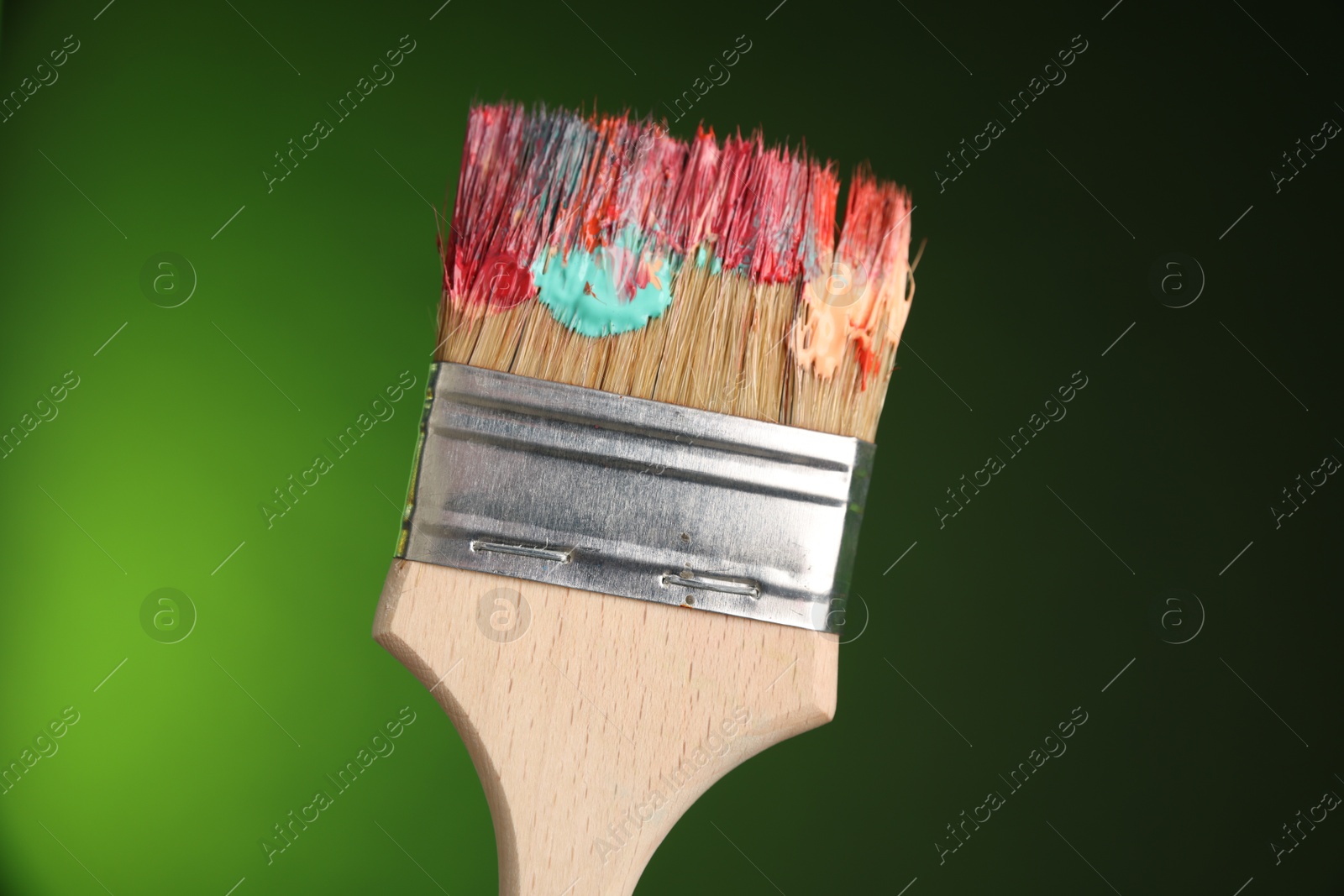 One dirty paintbrush on green background, closeup Photo of One dirty paintbrush on green background, closeup