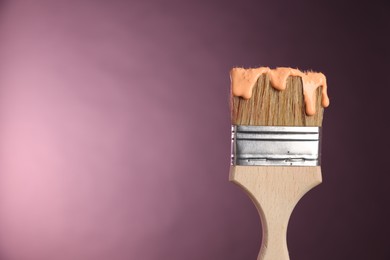 Photo of Brush with paint on pink background, closeup. Space for text