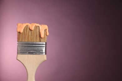Photo of Brush with paint on pink background, closeup. Space for text