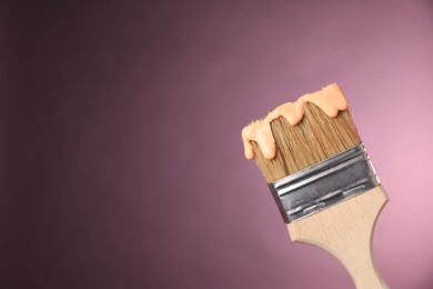 Photo of Brush with paint on pink background, closeup. Space for text