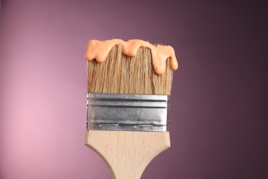 Photo of Brush with paint on pink background, closeup