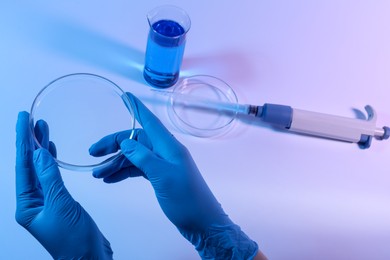 Photo of Scientist with Petri dish on light background, closeup