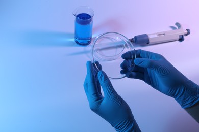 Photo of Scientist with Petri dish on light background, closeup