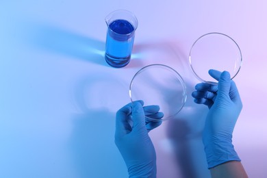 Photo of Scientist with Petri dishes on light background, closeup