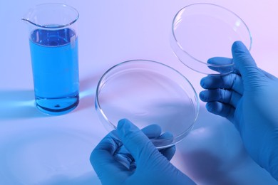Photo of Scientist with Petri dishes on light background, closeup