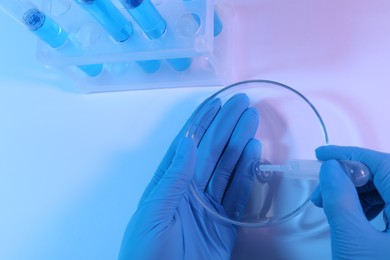 Photo of Scientist taking sample with pipette out of Petri dish on light background, closeup