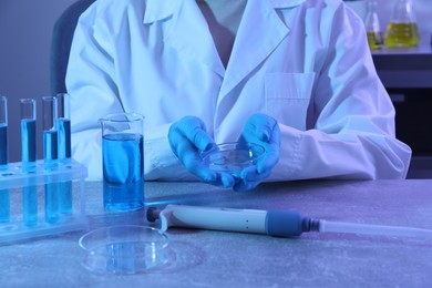 Photo of Scientist with Petri dish at table, closeup