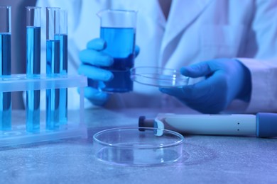 Photo of Scientist with Petri dish working at table, closeup