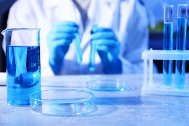 Photo of Petri dish and beaker with sample. Scientist working in laboratory, selective focus