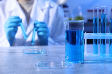 Photo of Petri dish and beaker with sample. Scientist working in laboratory, selective focus