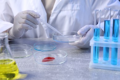 Photo of Scientist with Petri dishes and pipette at table, closeup