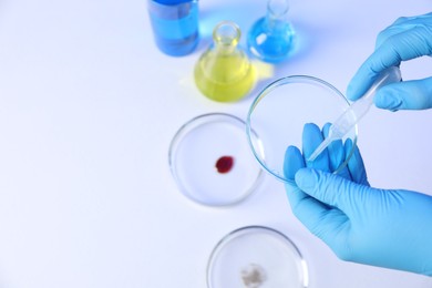Photo of Scientist with Petri dishes and pipette on white background, top view. Space for text