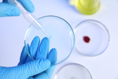 Photo of Scientist with Petri dishes and pipette on white background, closeup