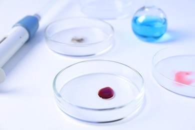 Photo of Petri dishes with samples and micropipette on white background, closeup