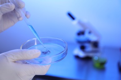 Photo of Scientist dripping liquid with pipette on Petri dish in laboratory, closeup. Space for text