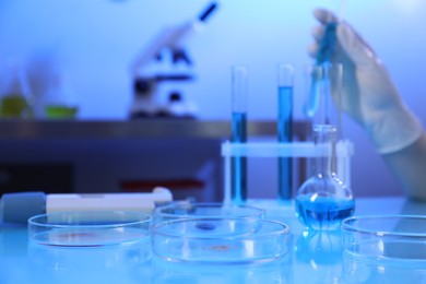 Photo of Petri dishes with samples on table. Scientist working in laboratory, selective focus