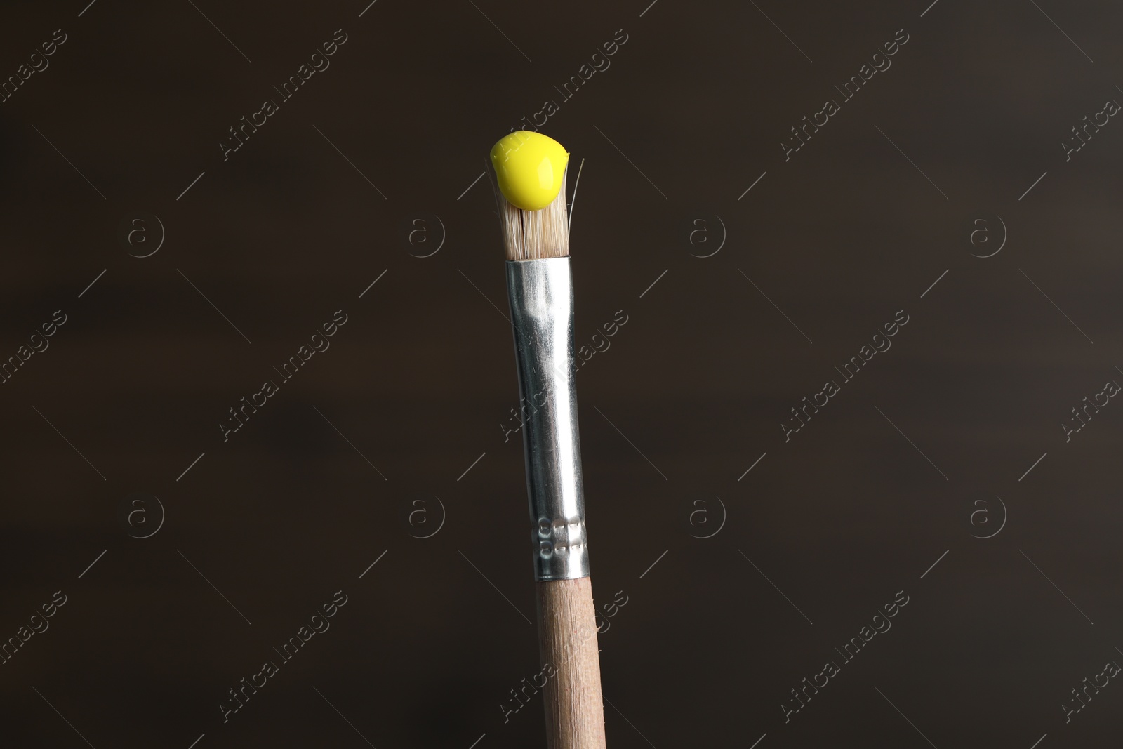 Brush with yellow paint on wooden background, closeup Photo of Brush with yellow paint on wooden background, closeup