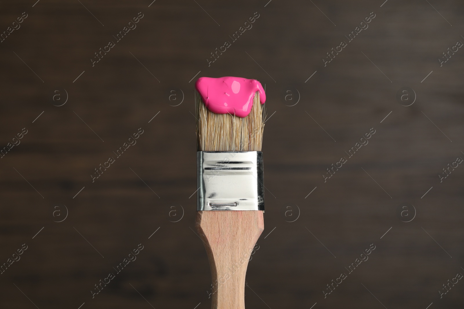 Brush with pink paint on wooden background, closeup Photo of Brush with pink paint on wooden background, closeup