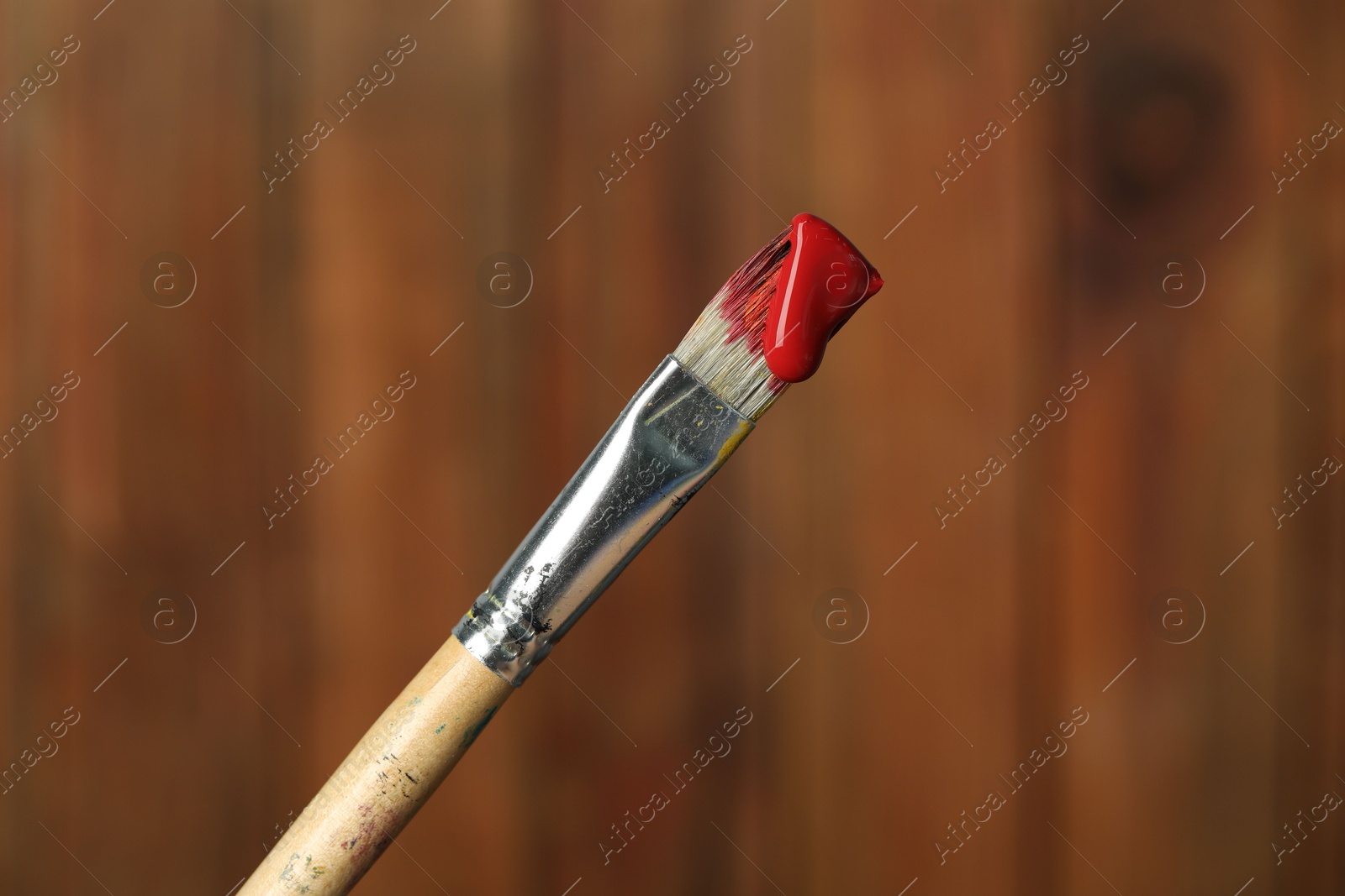 Brush with red paint on wooden background, closeup Photo of Brush with red paint on wooden background, closeup