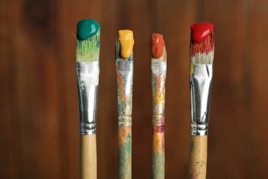 Photo of Many dirty paintbrushes on wooden background, closeup